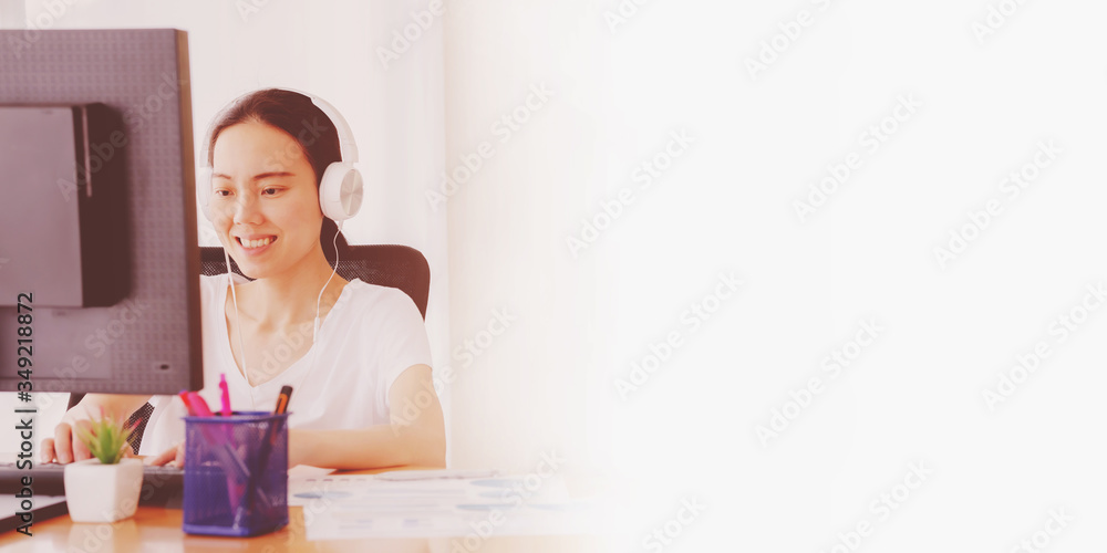 Young woman working on a start up business from a bright airy office at home reading information on her desktop monitor