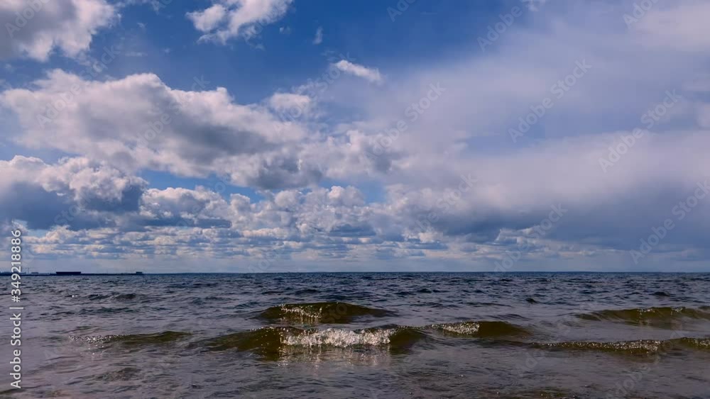 Beautiful blue sea with small waves and a blue sky with white clouds. Nature summer ocean background.