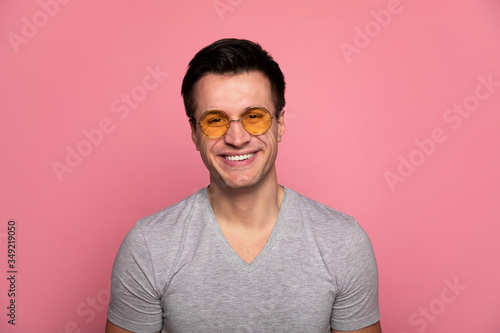 Summer look. Close-up photo of a young happy man in orange glasses, who is looking in the camera with a broad smile. © My Ocean studio