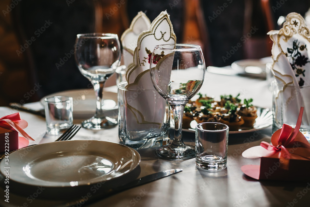 set of empty glasses and plates with Cutlery on a white tablecloth on the table in the restaurant set of empty glasses and plates with Cutlery on a white tablecloth on the table in the restaurant