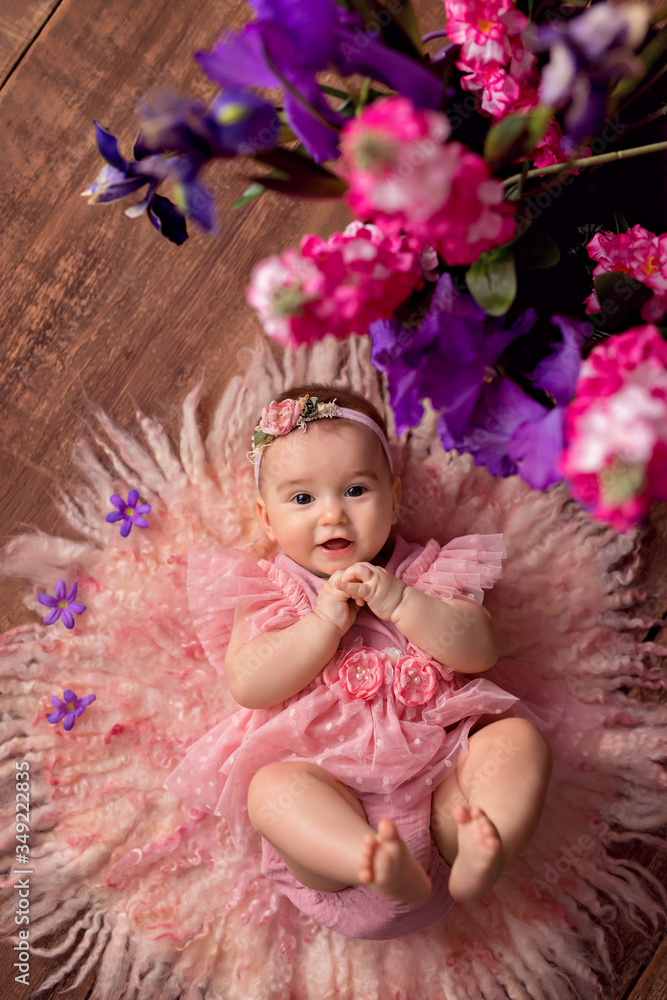 happy cute girl 3-5 months old lies on her back with flowers. Mothers Day. International Women's Day. happy cute girl 3-5 months old lies on her back with flowers. Mothers Day. International Women's Day.