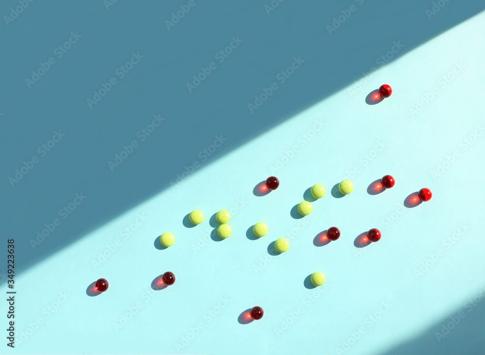 red capsules and round yellow tablets on a light blue surface illuminated by light cast a shadow. Vitamins, dietary supplements. Improvement, antibiotics, rise in price of medicines, red capsules and round yellow tablets on a light blue surface illuminated by light cast a shadow. Vitamins, dietary supplements. Improvement, antibiotics, rise in price of medicines,