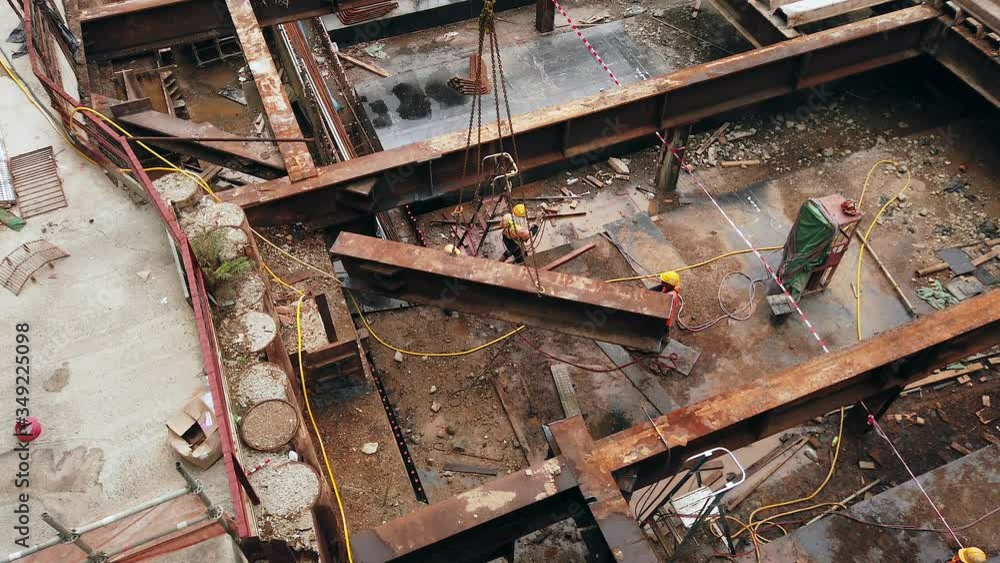 Mega Construction site in downtown Hong Kong with workers and Metal beam lifting operation, closeup aerial view. Mega Construction site in downtown Hong Kong with workers and Metal beam lifting operation, closeup aerial view.