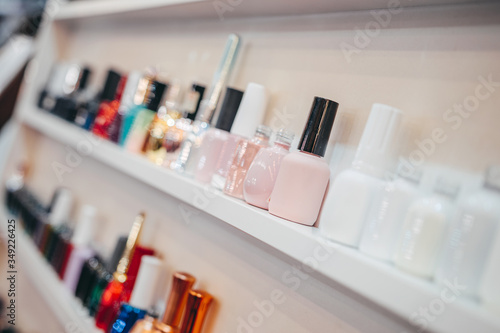 Various Bottles of nail polish on white shelf on shop. Group of bright nail polishes. Set of different nail varnishes on shelves in cosmetic store