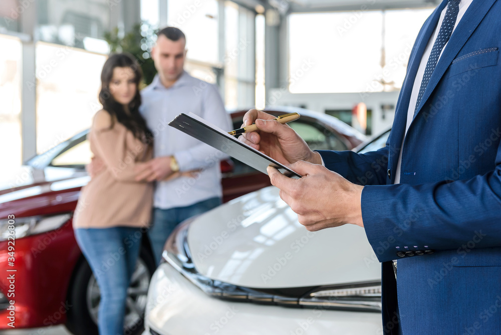 Dealer hands with clipboard and happy family behind Dealer hands with clipboard and happy family behind