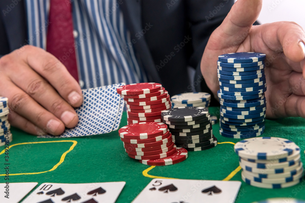 man play in casino with playing cards and chips at green table man play in casino with playing cards and chips at green table