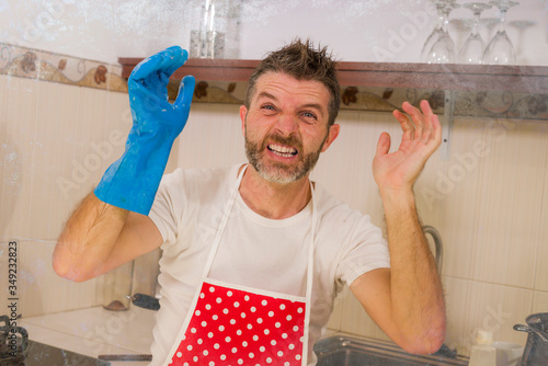 domestic chores stress - young attractive overworked and stressed home cook man in red apron hating dishwashing feeling upset and unhappy washing dishes frustrated photo