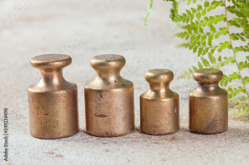 Four antique bronze weights for scales on concrete background.