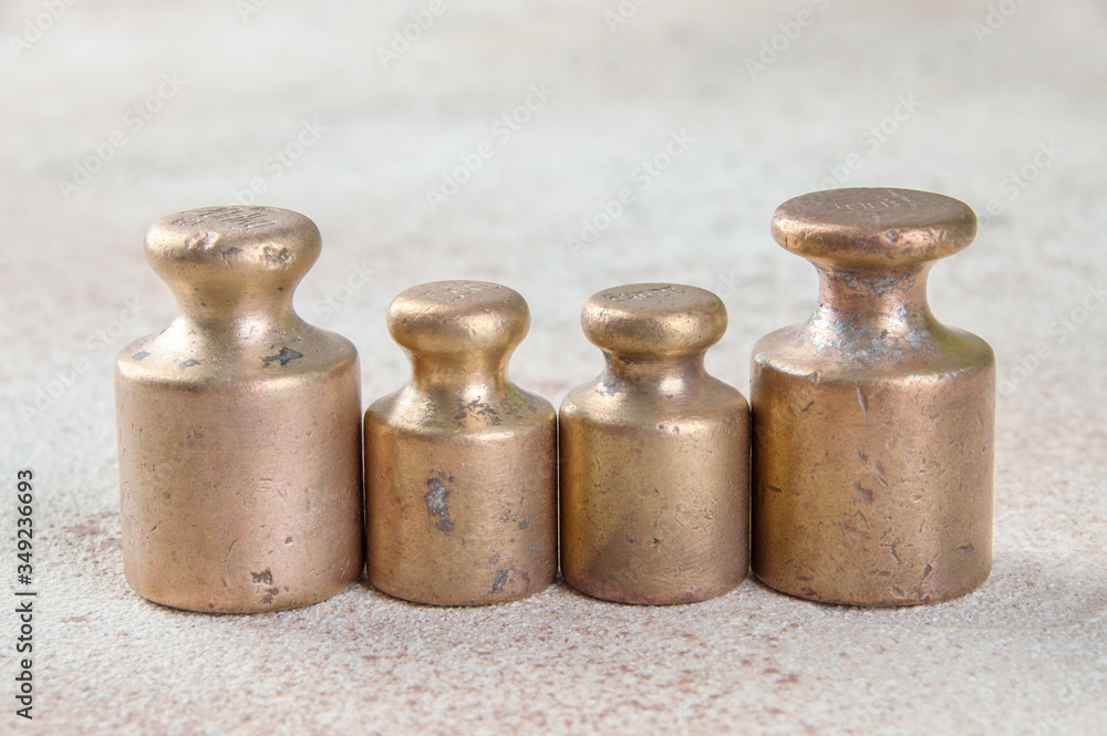 Four antique bronze weights for scales on concrete background. Four antique bronze weights for scales on concrete background.