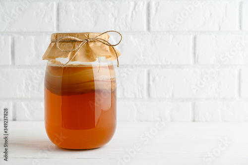 Homemade fermented kombucha tea in a glass jar on a background of a white brick wall. copy space
