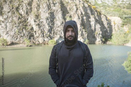 Hooded man poses near a lagoon
