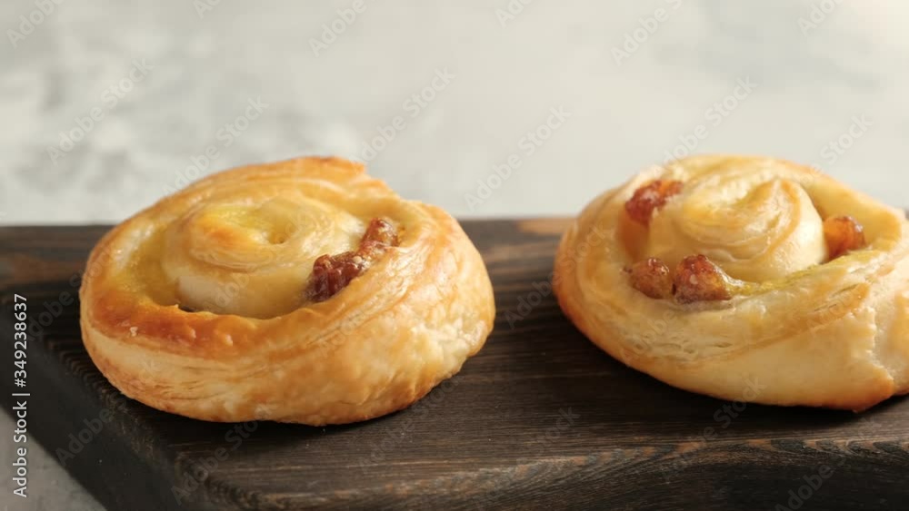 Fresh pastry sweet swirl buns with raisins on wooden board for breakfast or brunch. Party food concept. Camera slide right Fresh pastry sweet swirl buns with raisins on wooden board for breakfast or brunch. Party food concept. Camera slide right