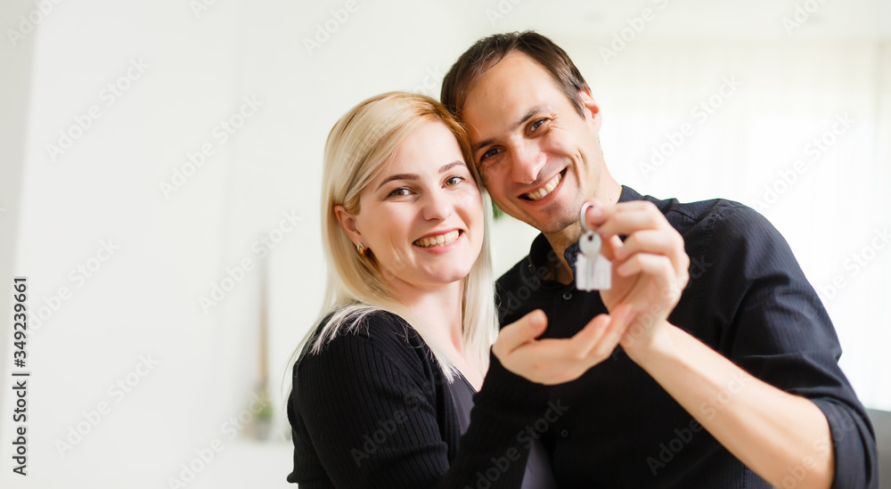 Happy smiling young couple showing a pair of keys of their new house Happy smiling young couple showing a pair of keys of their new house