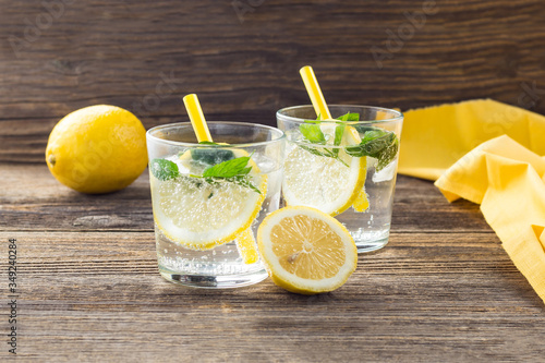 Lemonade or mojito cocktail with lemon and mint with ice. Cold summer refreshing drink decorated with yellow napkin