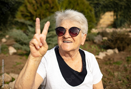 Closeup portrait of an old woman in sunglasses on the nature.