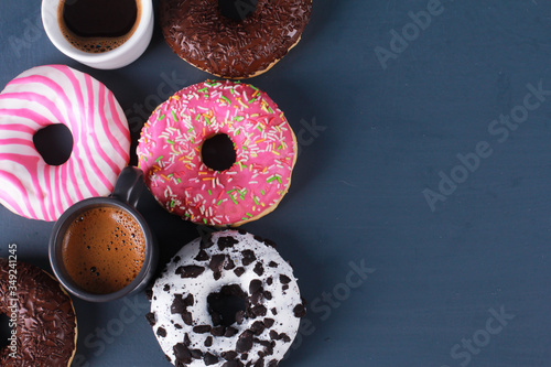 Assorted donuts and espresso cups on dark blue background. Top view, copy space. Bakery, coffee shop menu, breakfast, break concept