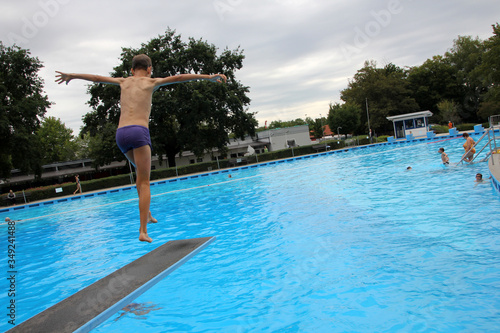 Ein Junge springt während den Sommertagen in einem Freibad vom Sprungbrett. © Marco