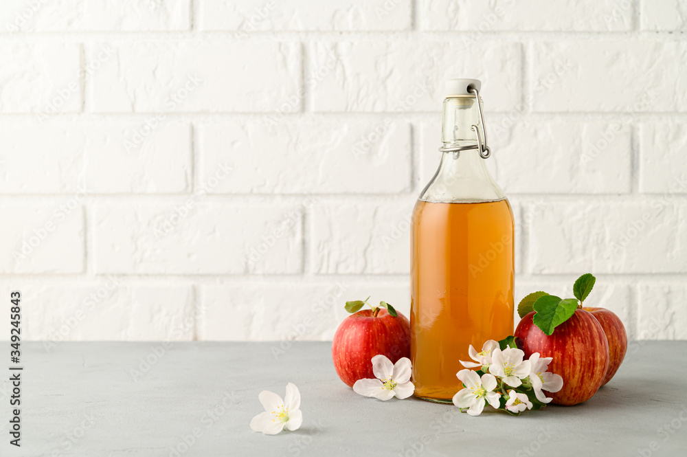 Homemade fermented kombucha drink in a glass bottle and fresh apples on a light gray stone table. A healthy probiotic drink. Copy space. Homemade fermented kombucha drink in a glass bottle and fresh apples on a light gray stone table. A healthy probiotic drink. Copy space.