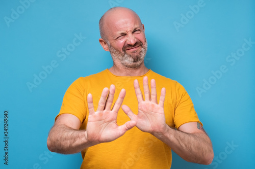 Photography Handsome mature man in yellow clothes making stop sign