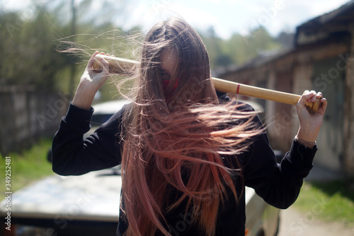 a young girl with a bat is standing near the car