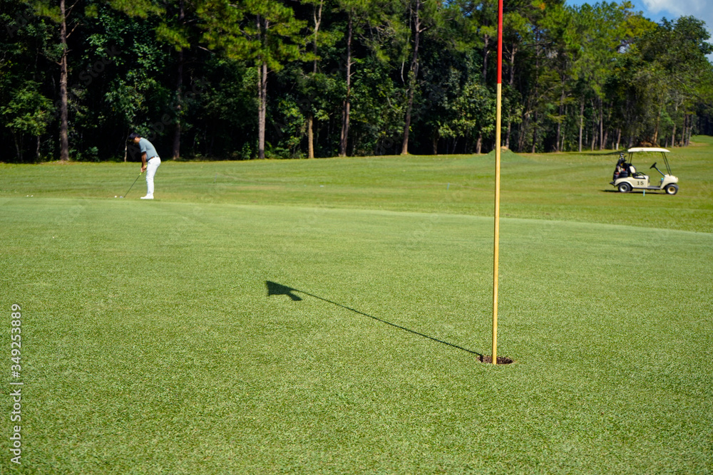 Obraz premium Golfer playing golf on the green grass with cart in the beautiful golf course at the sunshine.
