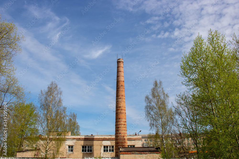 The chimney of an old boiler house against a clear blue sky