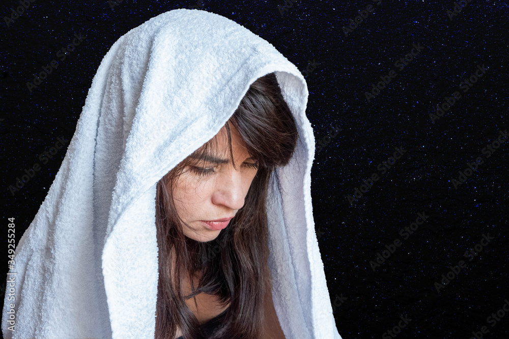 Obraz premium Close-up of a woman's face in a white scarf on a dark blue background, embarrassment, sadness, sadness