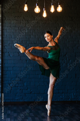 Fotografie Modern ballet dancer performing a ballet exercise on a dark studio background