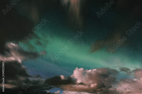Northern lights appear among the clouds.