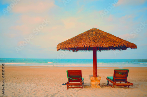 Fototapeta Naklejka Na Ścianę i Meble -  Two sun loungers and umbrella on the beach and evening light