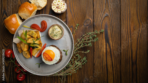 Beef medallions with egg, potatoes and peppers on a wooden background