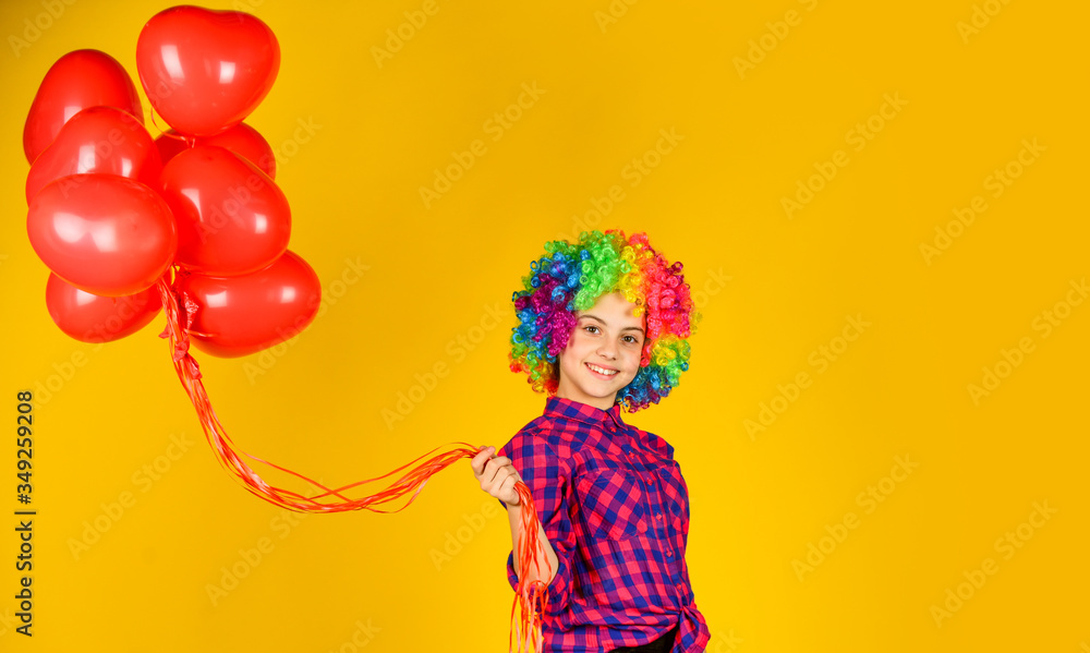 small girl in periwig. valentines day party. child wear rainbow wig hair yellow background. happy kid hold party balloons. heart balloons for love day. surprise for valentine. colorful and bright small girl in periwig. valentines day party. child wear rainbow wig hair yellow background. happy kid hold party balloons. heart balloons for love day. surprise for valentine. colorful and bright