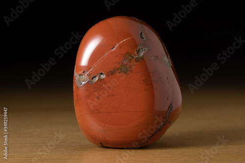 Polished red jasper gemstone from Brazil over a wooden table photo