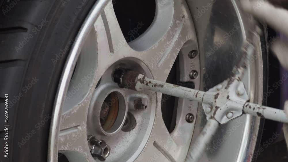 Unrecognizable man using a wrench tool to wheel nuts on a car. Close-up Unrecognizable man using a wrench tool to wheel nuts on a car. Close-up