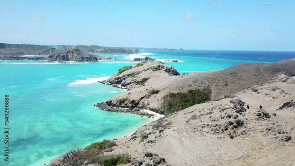 A drone shot of a couple walking on the cliffs, admiring the landscape in from of them in Tanjung Aan beach on Lombok, Indonesia. Barren cliffs. Turquoise color of water. Happiness and togetherness
A drone shot of a couple walking on the cliffs, admiring the landscape in from of them in Tanjung Aan beach on Lombok, Indonesia. Barren cliffs. Turquoise color of water. Happiness and togetherness
