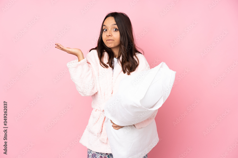 Young woman in pajamas isolated on pink background making doubts gesture Young woman in pajamas isolated on pink background making doubts gesture