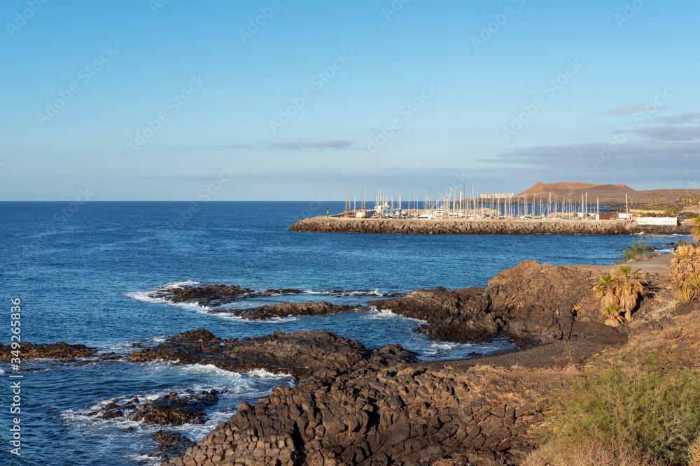 Obraz premium View of the San Miguel Marina, popular among year-round sailing aficionados and Montana Amarilla in the background, from eastern side of the coastal walking promenade, Tenerife, Canary Islands, Spain