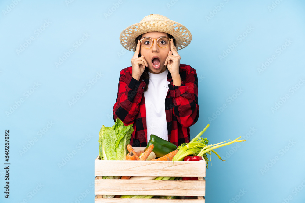 Young farmer Woman holding fresh vegetables in a wooden basket with glasses and surprised