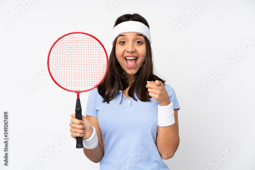 Young badminton player woman over isolated white background surprised and pointing front © luismolinero
