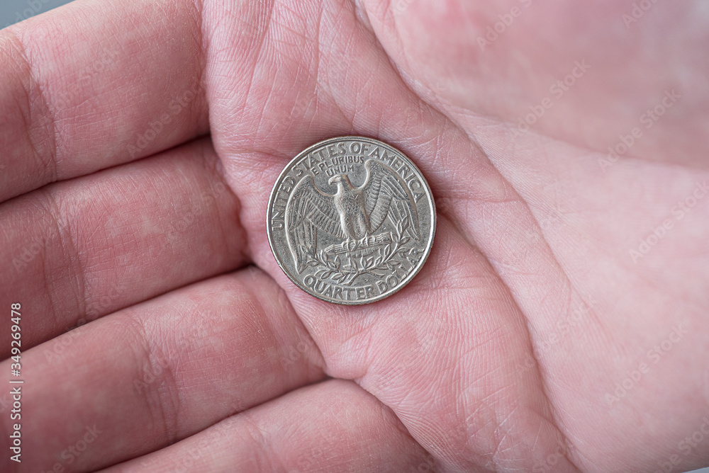 A man holding silver American quarter dollar coin, 25 cents, USA A man holding silver American quarter dollar coin, 25 cents, USA