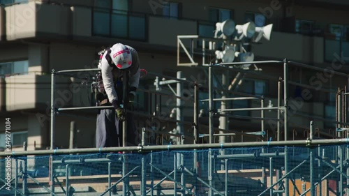 Construction worker on a building site in Japan. He is working with a spanner on scaffolding and is wearing a hard hat