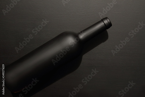 wine bottle black matte laying on black background, table, top view, copy space 