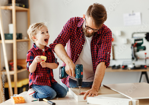 Happy kid helping father in carpentry studio.