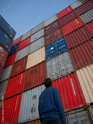 Man looking up at shipping containers in shipyard