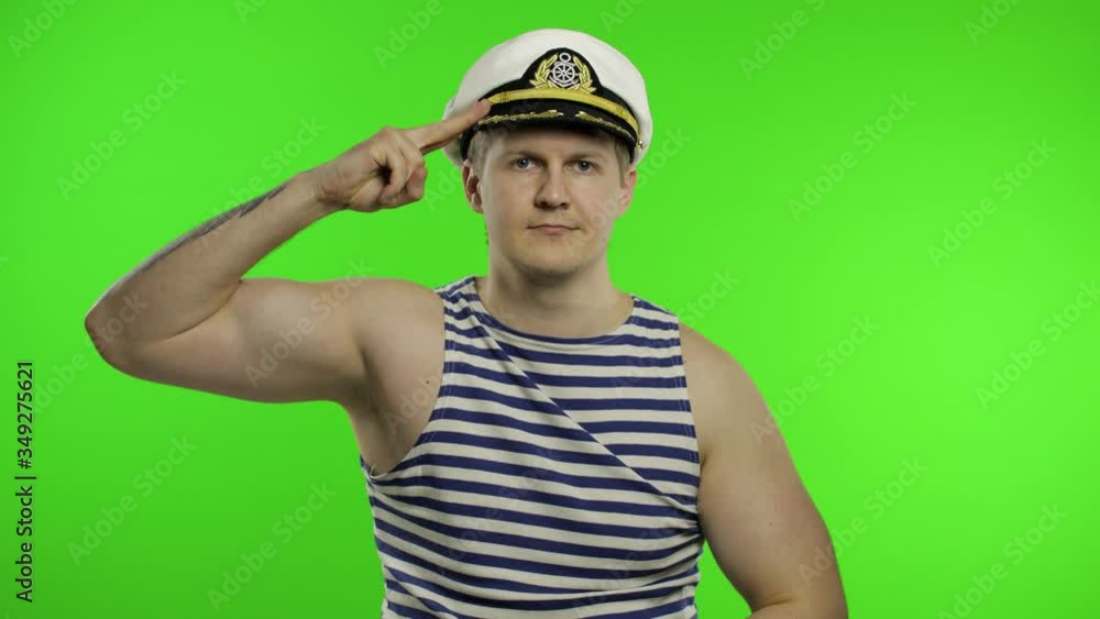 Young sailor man salutes with hand to camera. Seaman guy in sailor's vest Young sailor man salutes with hand to camera. Seaman guy in sailor's vest