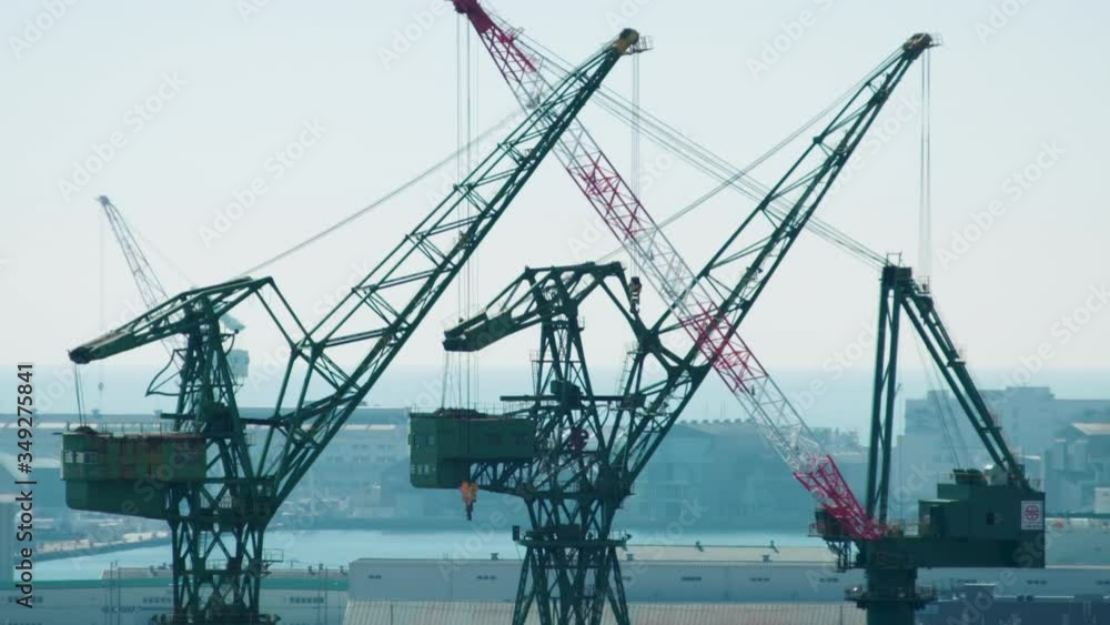 Heavy steel cranes against the Kobe skyline. Dock / harbour in Japan in background Heavy steel cranes against the Kobe skyline. Dock / harbour in Japan in background