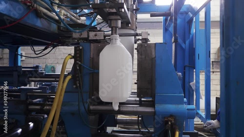 The process of blowing plastic tanks in extrusion equipment. Molten white plastic like a tube is placed in a press form and blowing the air and is give to shape of the bottle