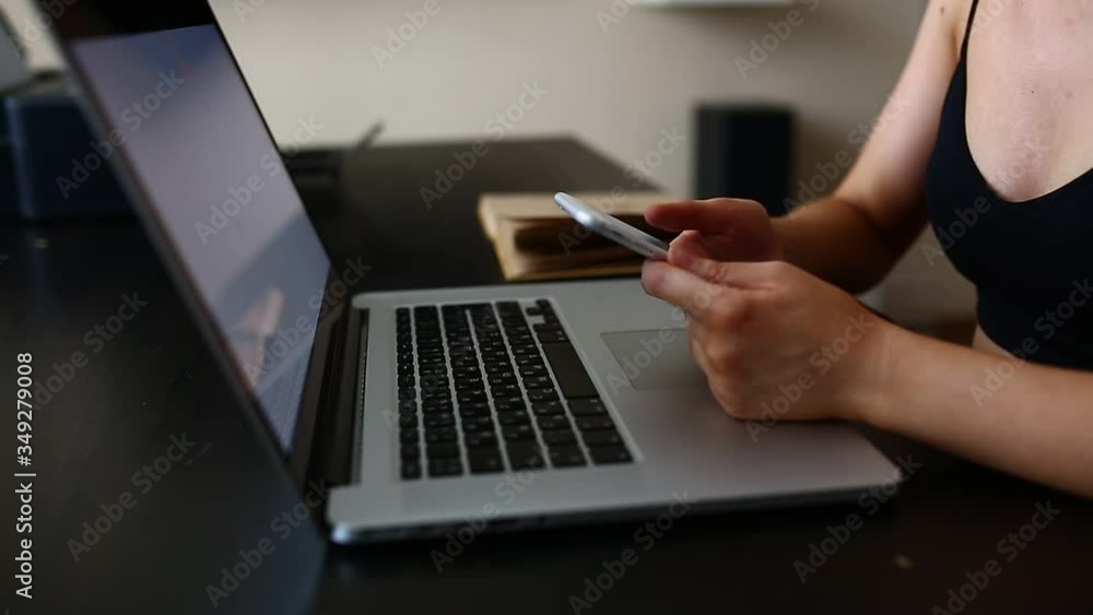 A cute pensive girl does work from home, looks at the information on the phone, looks into it and checks it against the information on the computer during quarantine and pandemic. A cute pensive girl does work from home, looks at the information on the phone, looks into it and checks it against the information on the computer during quarantine and pandemic.