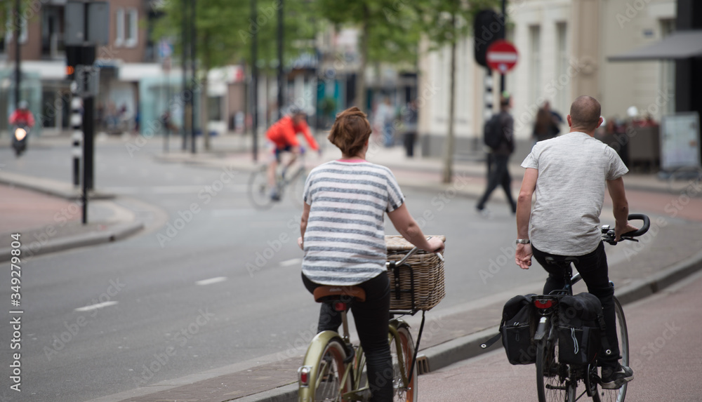 Anonymous woman and man cycling on bicycle lane in city centre Tilburg
