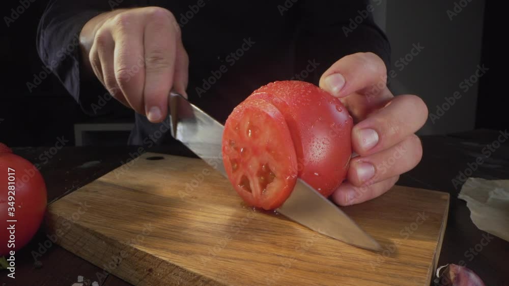 chef cuts ripe red tomato in a circles on the wooden board chef cuts ripe red tomato in a circles on the wooden board